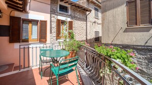 Un balcon avec une table et des chaises, un pot de fleurs et un mur en pierre.