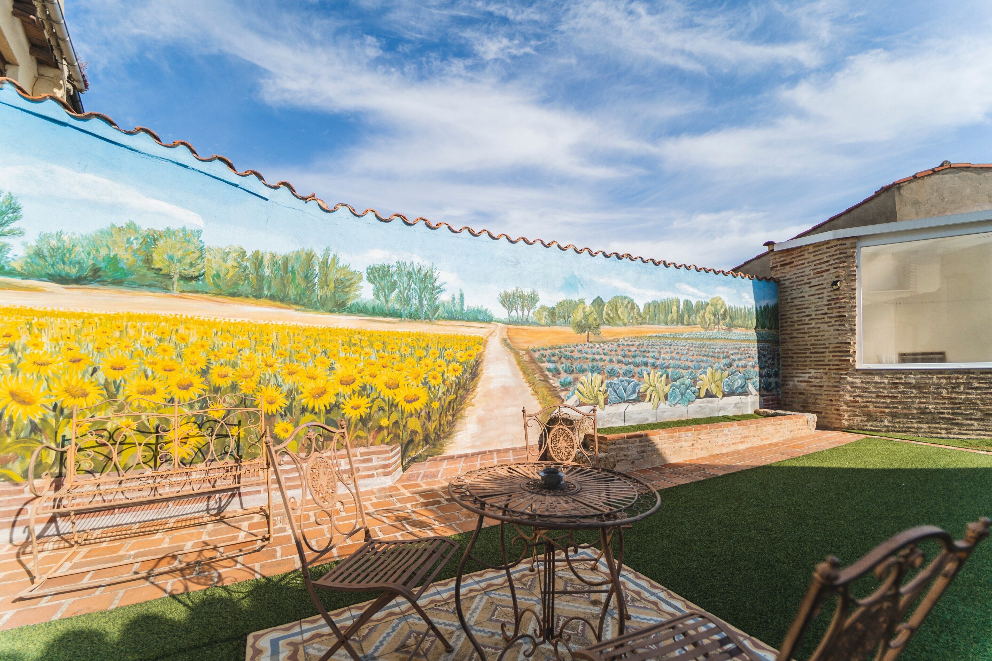 A patio with outdoor furniture, a brick pathway, and a sunflower field.