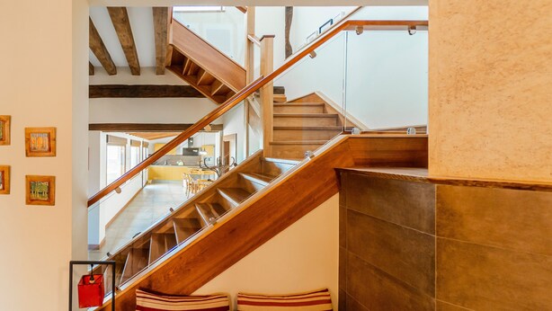 A staircase with wooden railings and a view of a kitchen area.