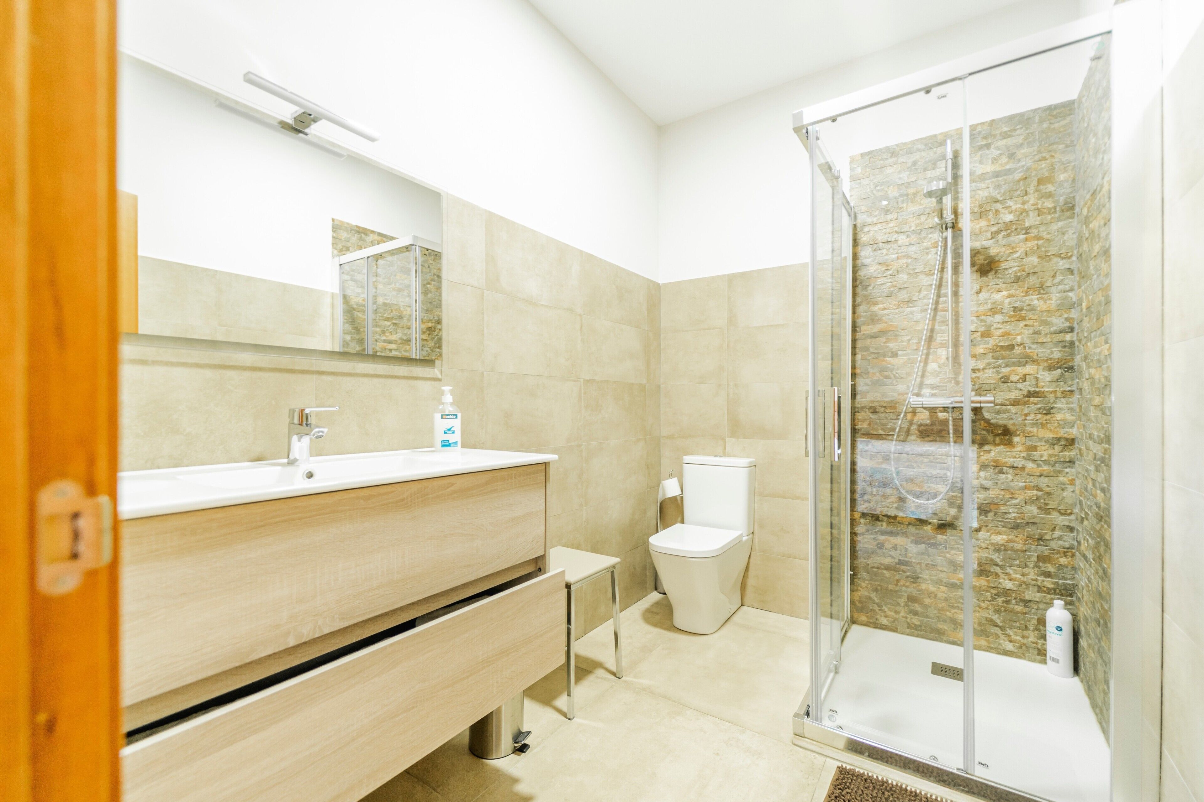 Une salle de bain moderne équipée d’une douche, de toilettes, d’un meuble-lavabo et d’un miroir.