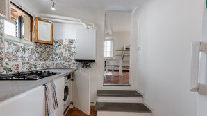 Eine schmale Küche mit einem Gasherd, einer Waschmaschine und einem Holzschrank.