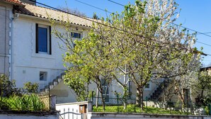 A building with a tiled roof, a staircase, and a tree in front.