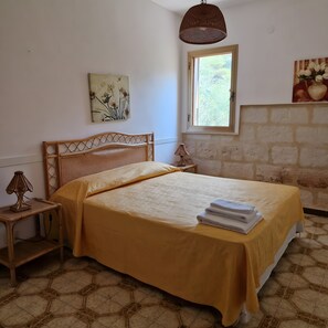 A bedroom with a bed, a window, a wall painting, and a lamp.