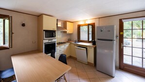 Une cuisine compacte comprenant une table à manger, un four à micro-ondes, une cuisinière, un évier et un réfrigérateur.