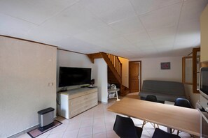 A compact living space with a dining area, a television, a staircase, and a sofa. - Duplex in the heart of the maquis with mountain views, Wi-Fi and air conditioning (Meria)