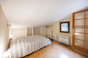 Un dormitorio con cama, radiador, ventana y puerta.