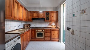 A kitchen with wooden cabinets, a built-in oven, a washing machine, and a tiled backsplash.
