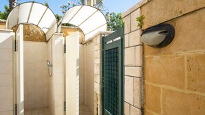 A private bathroom with a shower, toilet, and a green gate.