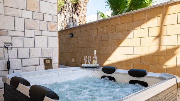 A hot tub with water jets, a remote control, and a glass set on a tray.