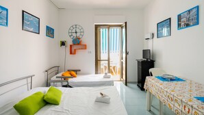 Une chambre d’hôtel avec deux lits, une table, une télévision et une porte donnant sur un balcon.