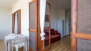Ein Zimmer mit Esstisch, Stühlen, einer Couch und einer Schiebetür.