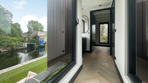 Een modern interieur met uitzicht op een gracht en groen.