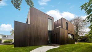 Een modern huis met een uniek architectonisch ontwerp, met een combinatie van houten panelen en glasramen.