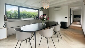 Een moderne keuken met een groot raam, een eettafel met stoelen en een hanglamp.
