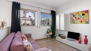 Ett vardagsrum med en soffa, en tv och en tavla på väggen.