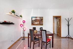 A dining area with a wooden table, chairs, a floor lamp, and a painting on the wall.
