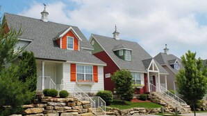 A row of houses with stone steps leading to the front door, a small porch, and a well-maintained lawn. - Two Bedroom Cottage, Luxury Resort, Branson, Missouri  4044650 (Branson)