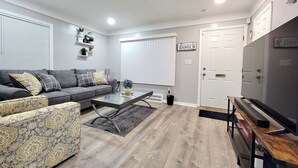 Ein modernes Wohnzimmer mit grauem Sofa, einem Couchtisch und einer TV-Konsole.