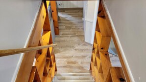 Eine Holztreppe mit Metallgeländern, die zu einer höheren Etage führt.