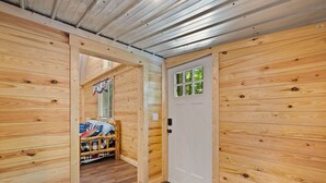 Ein Holzinterieur mit einem Bett, einer weißen Tür und einem Fenster mit Blick.