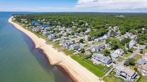 Vue aérienne d’une zone résidentielle côtière, avec des maisons, une plage et un lac.