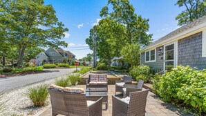 Une terrasse avec des meubles en osier, un panneau de signalisation indiquant un arrêt obligatoire, et des maisons en arrière-plan.