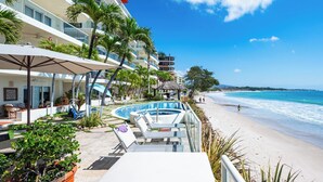 A resort with a pool, beach, and palm trees.