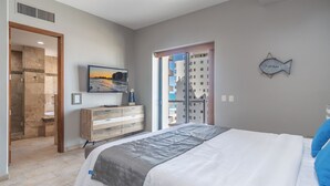 A bedroom with a bed, a dresser, a TV, and a view of buildings through an open door. - Las Palomas Phase II Cortez 507 Exceptional Oceanview 3BR 3BA Unit (Puerto Peñasco)