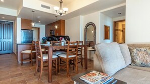 A modern living room with a sofa, a coffee table with magazines, and a dining area with wooden chairs and a table.