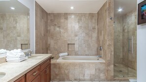 Une salle de bain moderne avec une baignoire sur pieds, une douche à parois de verre et un meuble-lavabo en marbre.