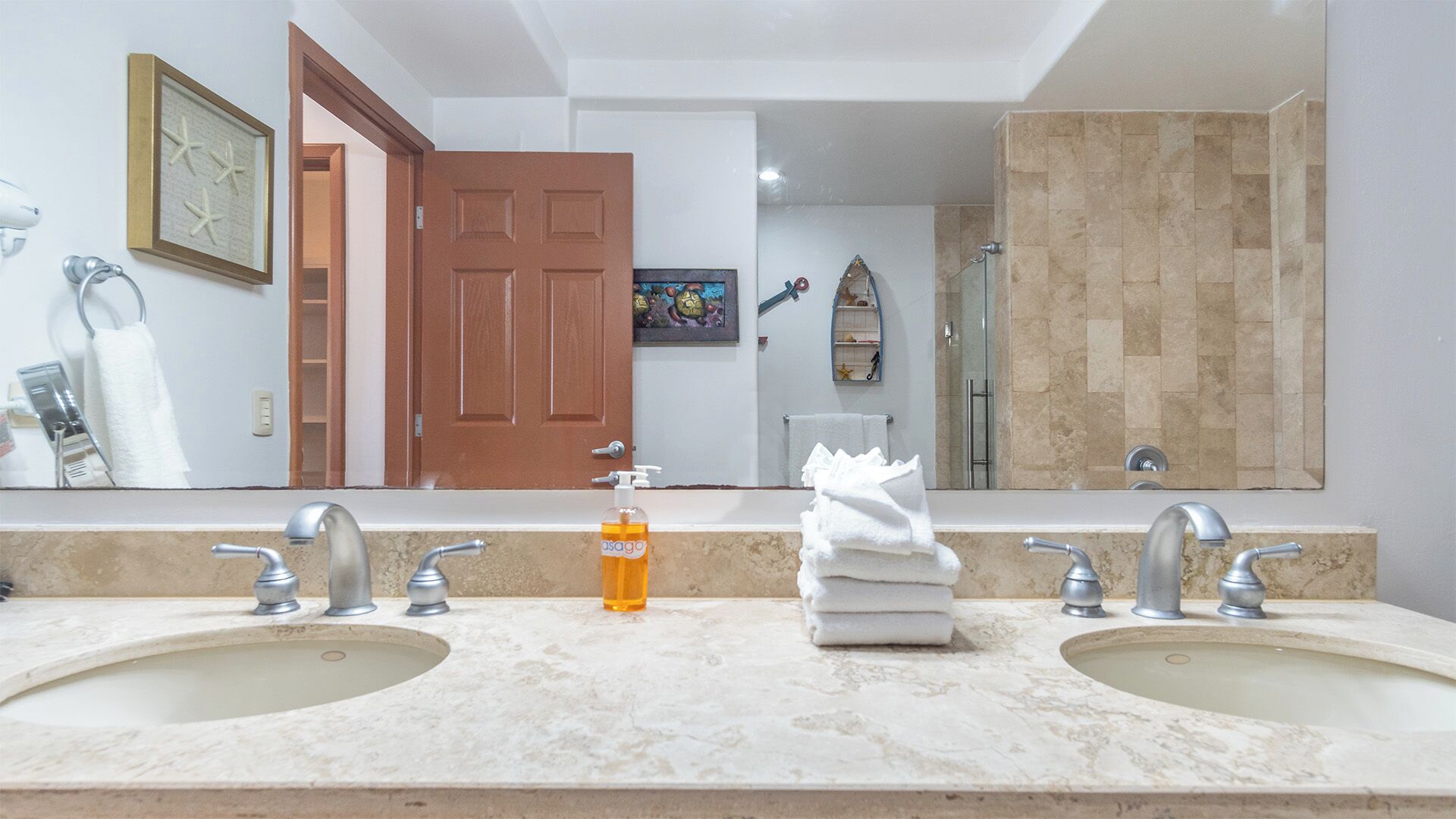 A bathroom with two sinks, a large mirror, and a shower area.