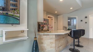 A modern kitchen with a marble countertop, a brick accent wall, and a built-in TV. - Las Palomas Opalo 502 Exceptional Oceanview 1BR 1BA Unit (Puerto Peñasco)