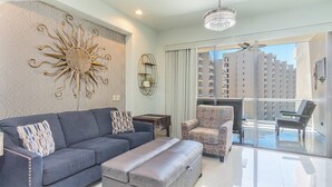 A modern living room with a grey sofa, patterned cushions, a decorative wall piece, a small side table, and a patterned armchair. - Las Palomas Opalo 502 Exceptional Oceanview 1BR 1BA Unit (Puerto Peñasco)
