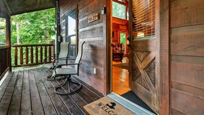 A wooden cabin with a porch, a welcome mat, and a door with a number sign. - Family friendly cabin in great location! Arcade~Hot Tub~Foosball~Fireplace (Sevierville)