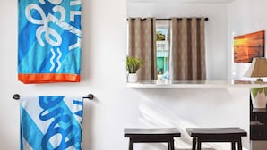 Quarto com uma grande janela, um vaso de planta e vista para um edifício.