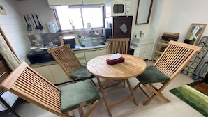A compact kitchen with a dining area, including a round wooden table, two chairs, and a microwave. - 1minute walk to stataion, direct bus to Haneda Airport! Easy access! (大田区)