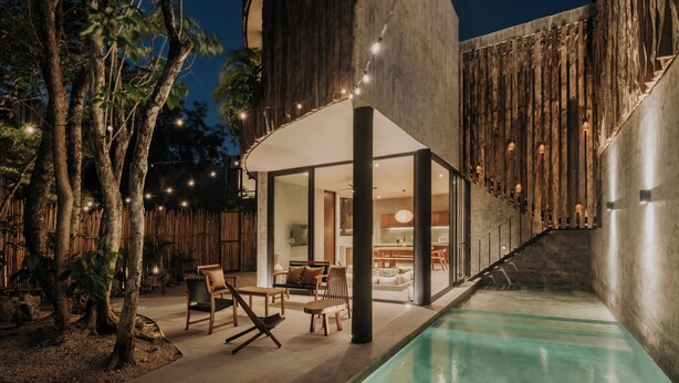 Ein moderner Außenbereich mit Pool, Holzmöbeln und Lichterketten.