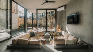 Ein modernes Wohnzimmer mit einer großen Couch, einem Couchtisch und einem Deckenventilator.