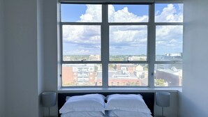 A bedroom with a large window, a bed with white linens, and two bedside lamps.