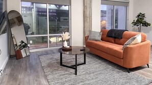 A modern living room with a sofa, coffee table, and large windows. - StayAE - High Rise (Baton Rouge)