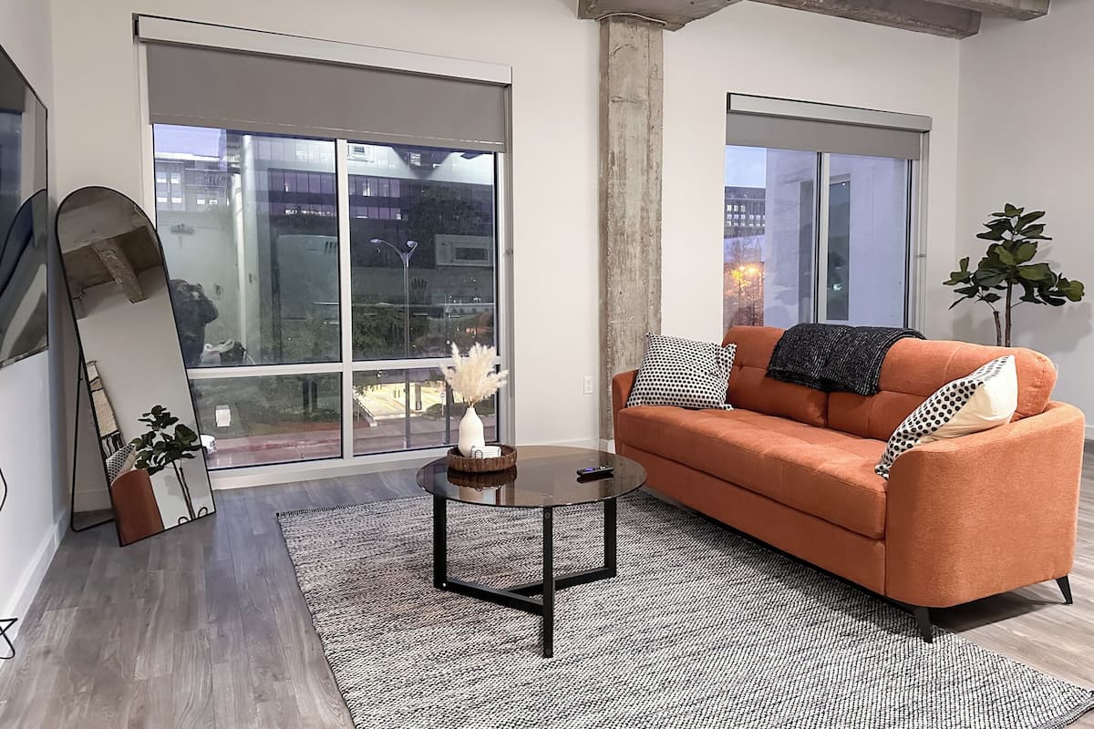 A modern living room with a sofa, coffee table, and large windows.