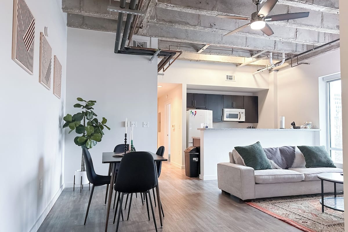 A modern living space with a dining area, kitchen, and seating area.