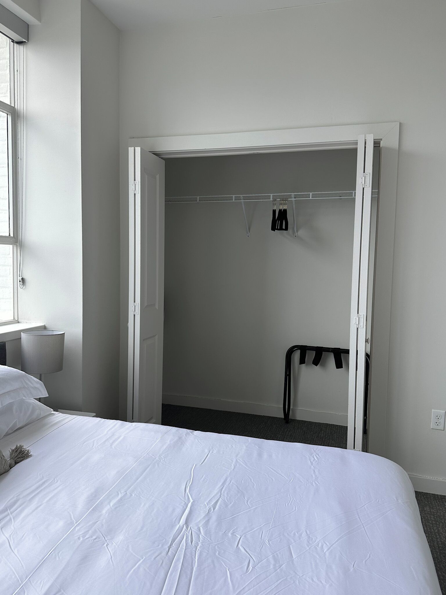 Une chambre à coucher avec un lit, une armoire et une petite table avec une lampe.