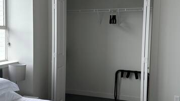Une chambre à coucher avec un lit, une armoire et une petite table avec une lampe.