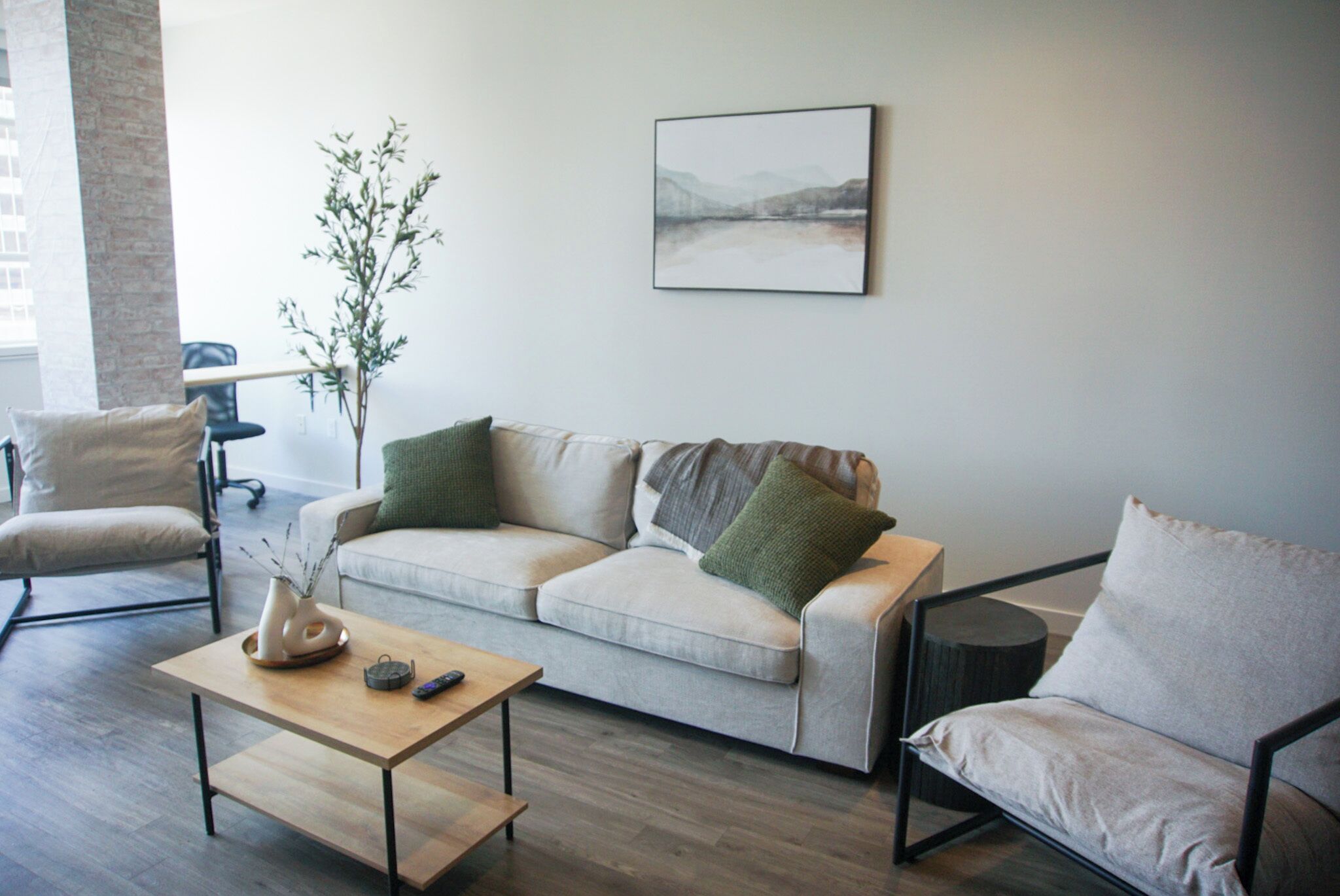 Una sala de estar con un sofá, dos sillones, una mesa de centro y una planta.