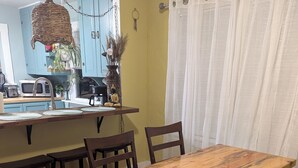 A dining area with a wooden table and chairs, a kitchen in the background, and a patterned rug on the floor. - Remodeled Historical Home 2 blocks from CSU campus and 3 blocks to Old Town  (Fort Collins)