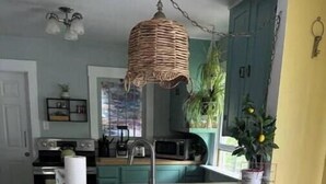 A kitchen with a wooden island, three stools, and a hanging light fixture. - Remodeled Historical Home 2 blocks from CSU campus and 3 blocks to Old Town  (Fort Collins)