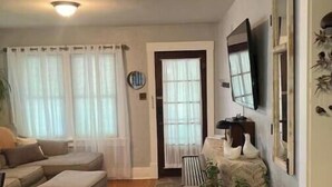 A living room with a sectional sofa, a small table, and a television mounted on the wall. - Remodeled Historical Home 2 blocks from CSU campus and 3 blocks to Old Town  (Fort Collins)