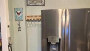 A kitchen with a stainless steel refrigerator, a small trash bin, and a water dispenser. - Remodeled Historical Home 2 blocks from CSU campus and 3 blocks to Old Town  (Fort Collins)