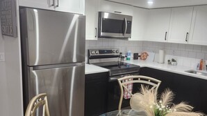Una cocina moderna con electrodomésticos de acero inoxidable, una mesa de comedor de vidrio y un jarrón decorativo.